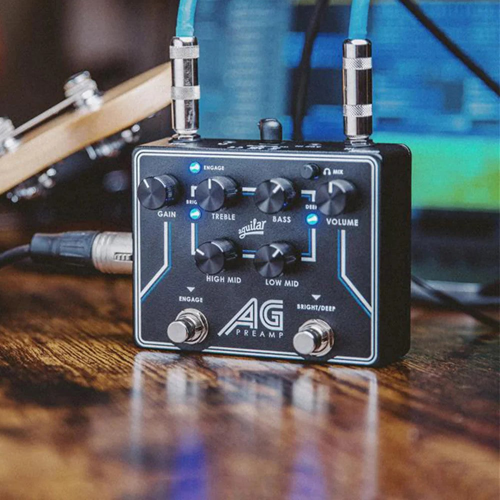 Angled front view of Aguilar AG Preamp Pedal on wooden surface with cables attached