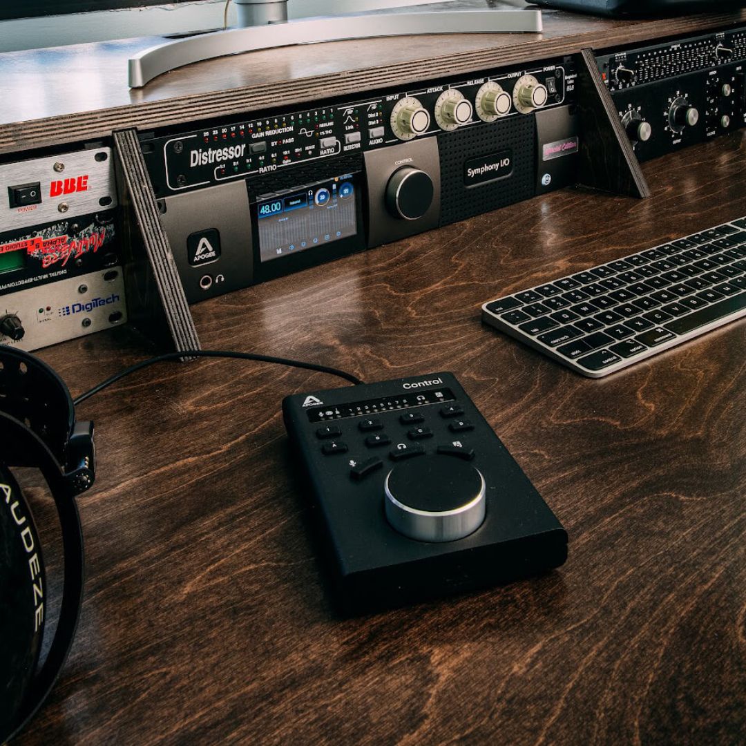 Music production equipment on a wooden desk with a keyboard and headphones.
