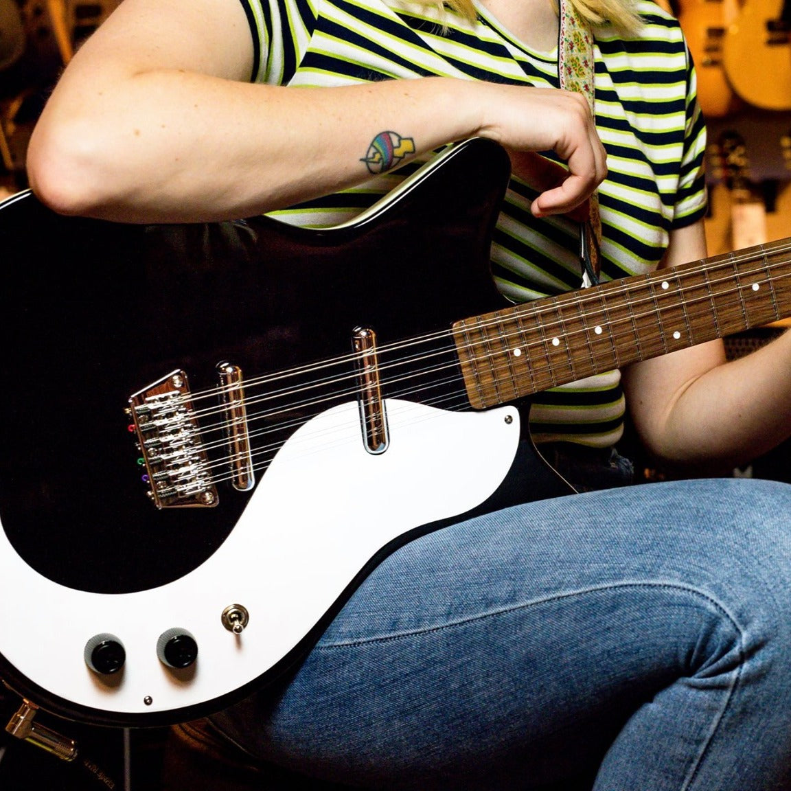 Close up view of Danelectro 59 12-String Electric Guitar Black in playing position with guitarist in guitar shop