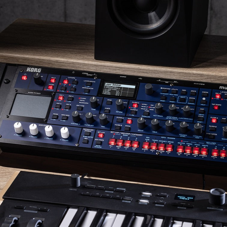 Front view of Korg multi/poly module in equipment rack with monitor speaker and keyboards in studio