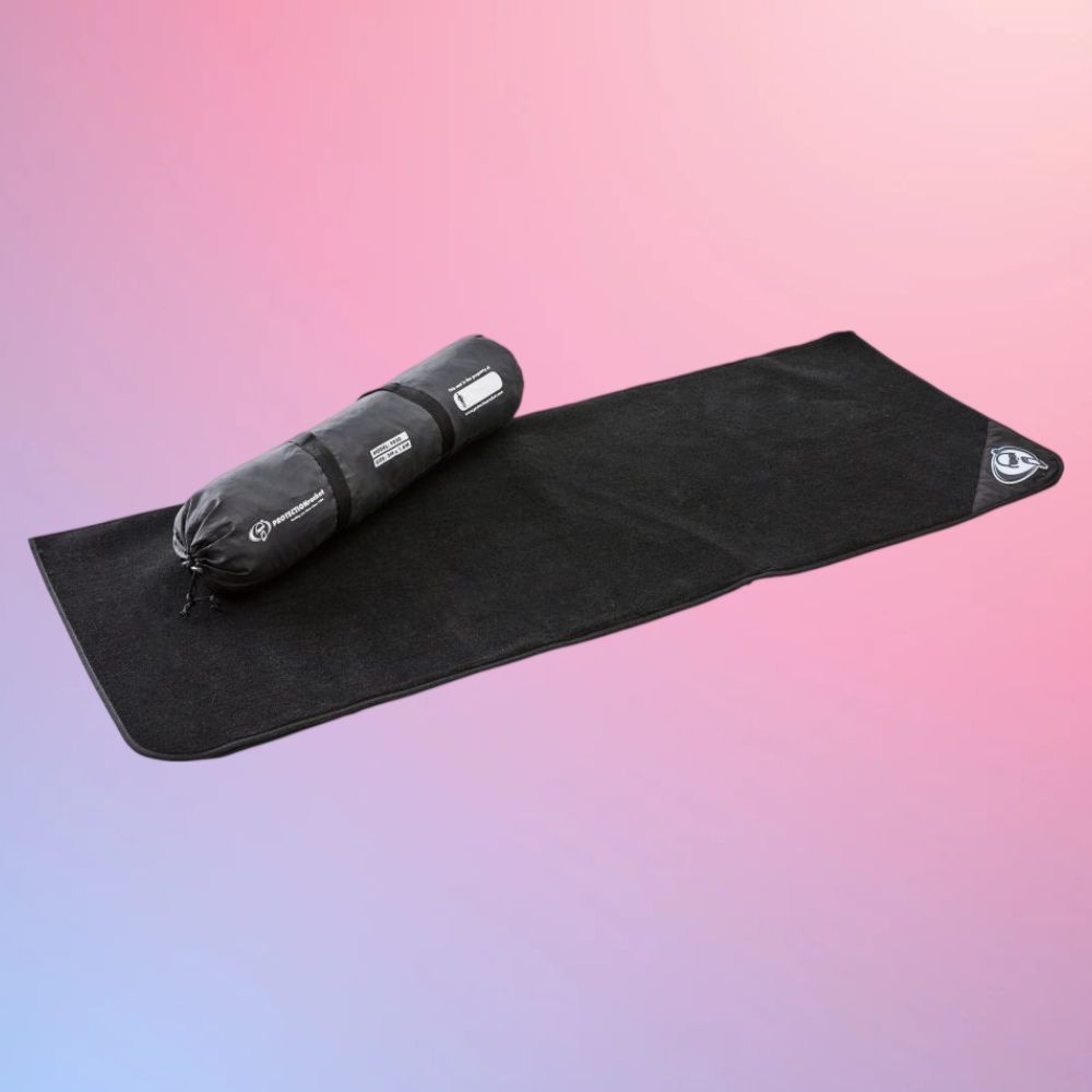 Unrolled view of Protection Racket Folding Drum Mat 6.56' x 5.25' with carrying bag on pink and purple gradient background