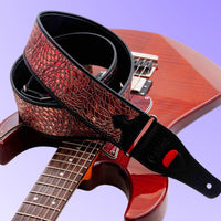 Curled view of RightOn Alien Guitar Strap Red on top of guitar with purple background