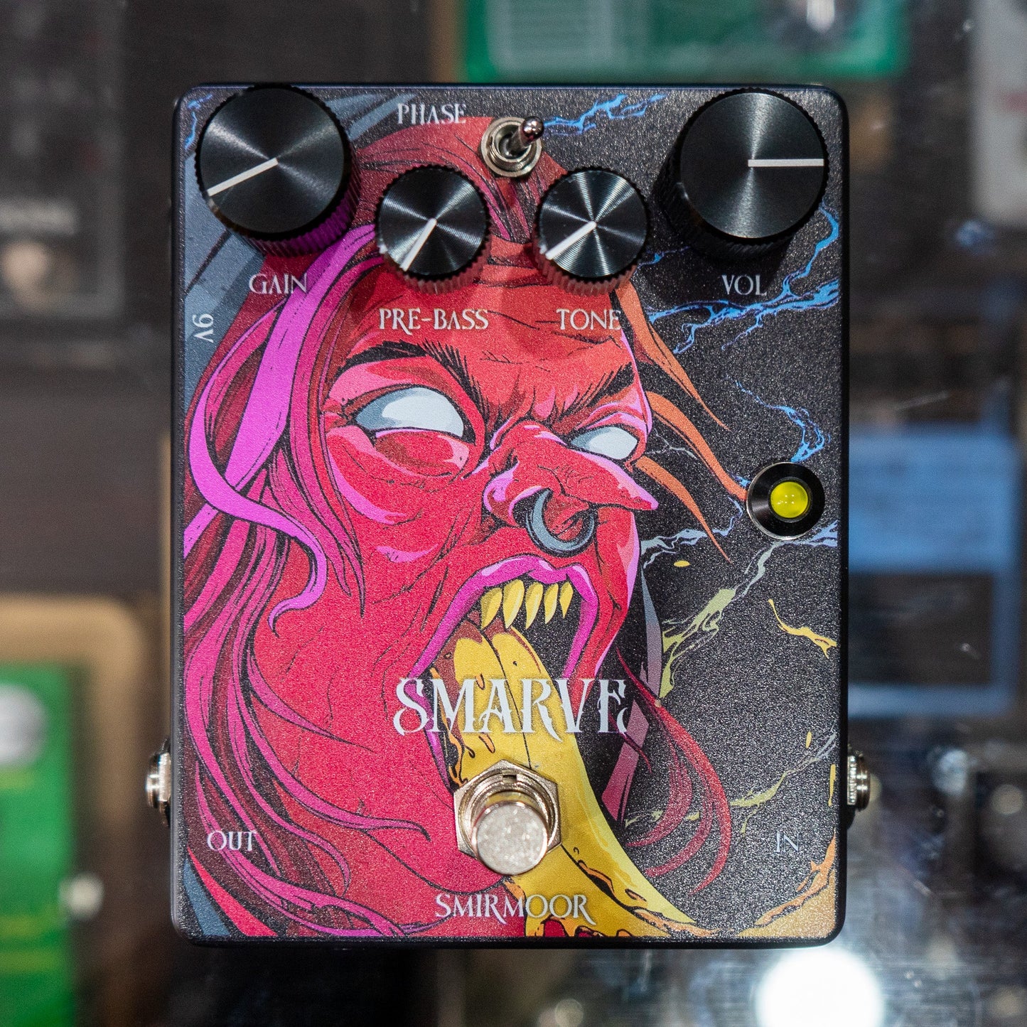 Front view of Smirmoor Smarve Pedal on glass case with pedals in the background