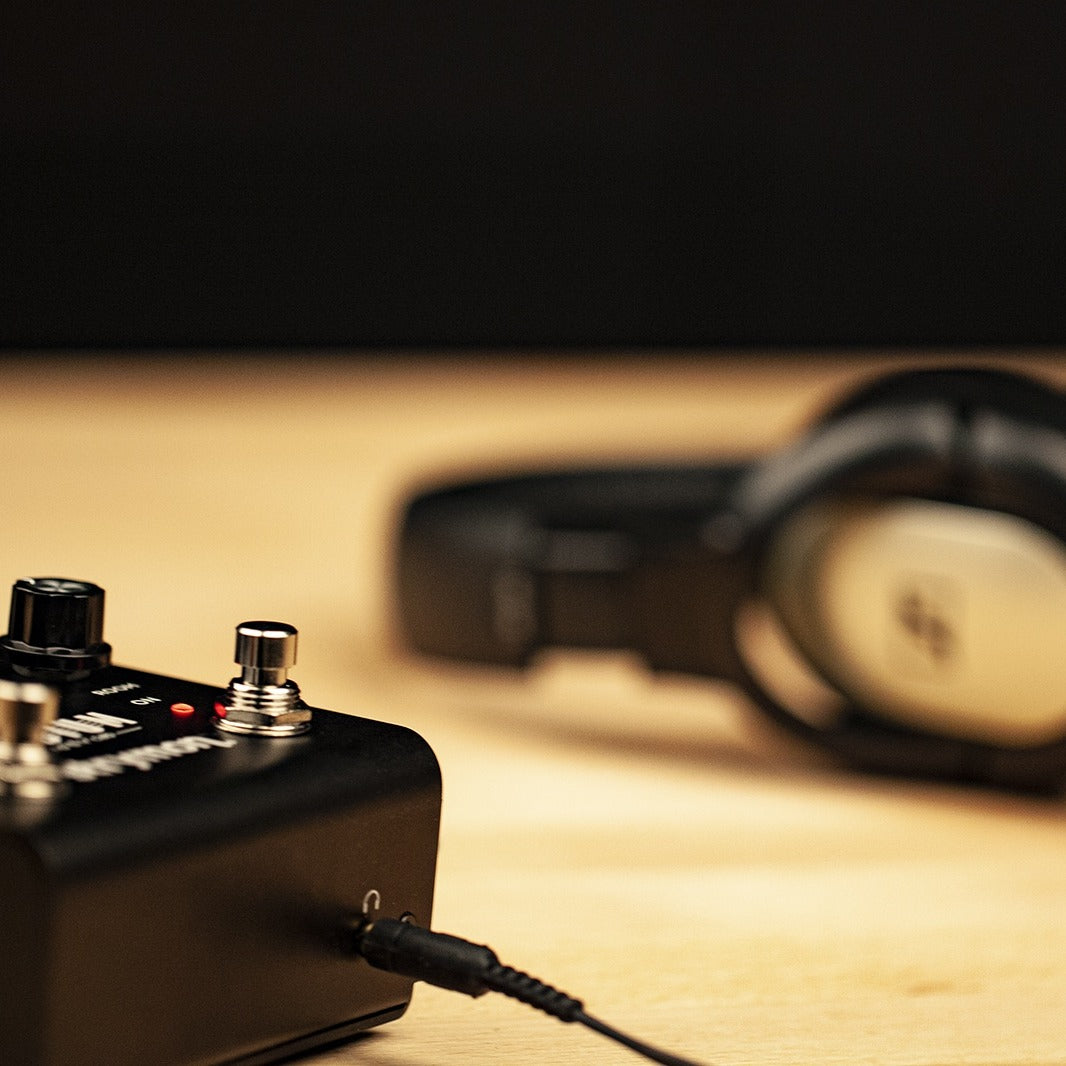 Strymon Iridium connected to headphones on wooden desk with black background