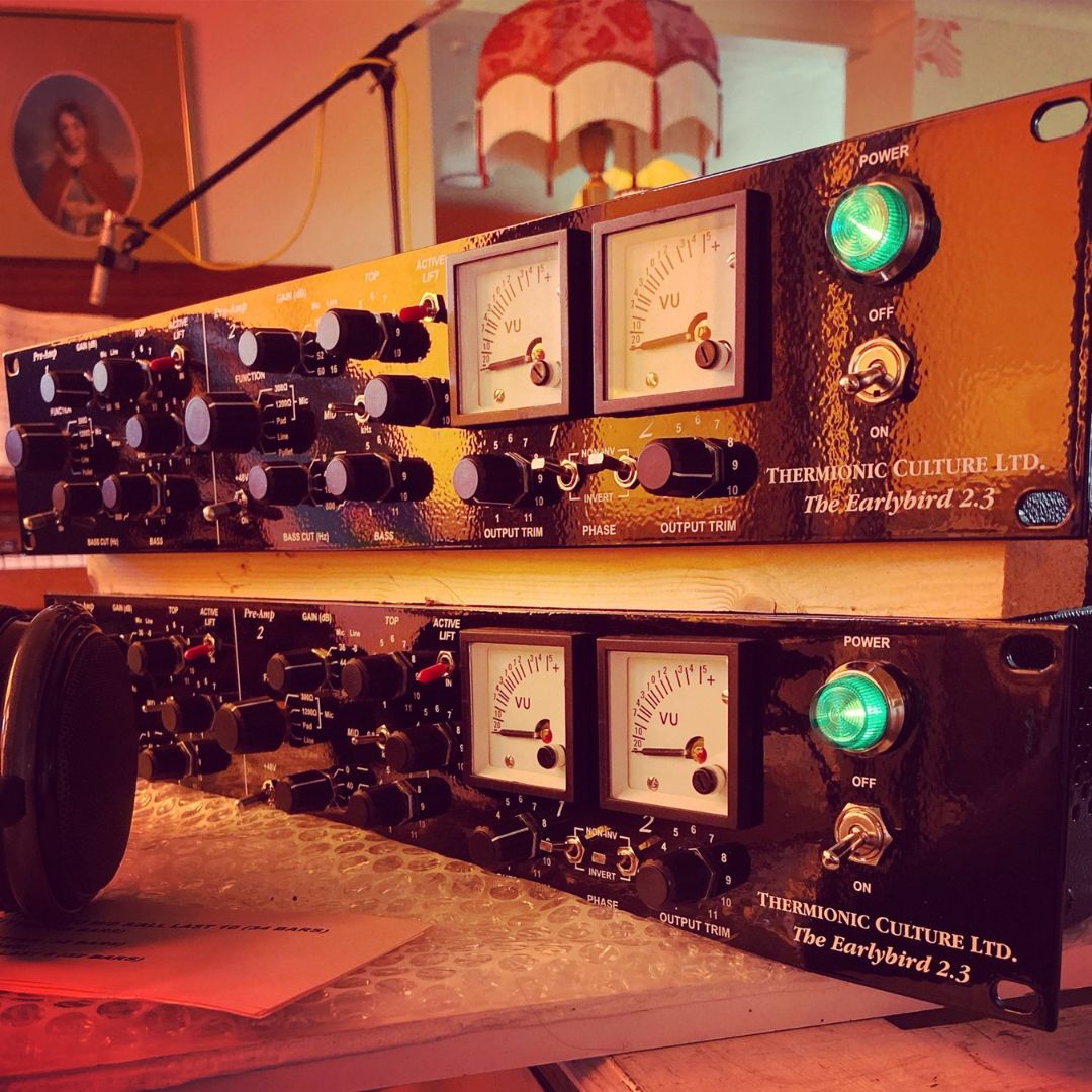 Close up shot of two rackmount effects stacked on top of each other on top of wooden table with a studio background