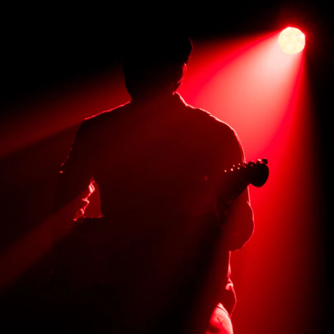 Hanging ADJ FOC734 Focus Flex L7 40W LED Moving Head beaming red spotlight on guitarist in dark venue