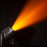 Angled view of ADJ HYD869 Hydro Hybrid IP65-Rated LED Moving Head beaming orange light upward in dark room