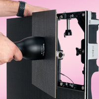 Hands installing the video panels of ADJ VS2 9X5 Video System on pink background