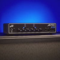 Angled front view of Aguilar AG 700 Bass Amp Head on speaker cab with blue background