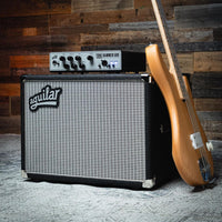 Angled front view of Aguilar DB 112 Bass Cabinet with amp head on top of it and bass leaning on it in studio