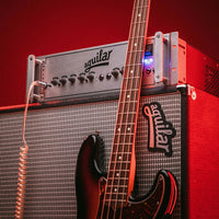 Angled front view of Aguilar DB 751 Bass Amp Head on top of speaker cab with bass leaning on it in red-lit studio