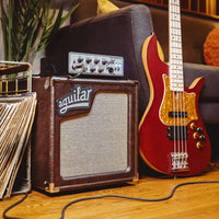 Angled front view of Aguilar SL 110 Bass Cabinet Chocolate Brown on with bass amp head on top of it and bass beside it in living room
