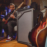 Angled front view of Aguilar SL 212 Bass Cabinet with amp head on top of it and bassist playing through it in studio