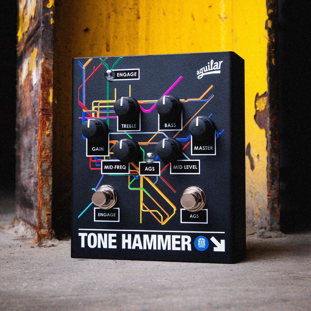 Angled front view of Aguilar Tone Hammer Limited Subway Edition Pedal on concrete surface with rusty yellow metal background