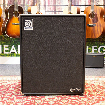 Front view of Ampeg HSVT-410HLF Heritage 4x10" 500W Bass Cabinet on red carpet with guitars hanging in the background