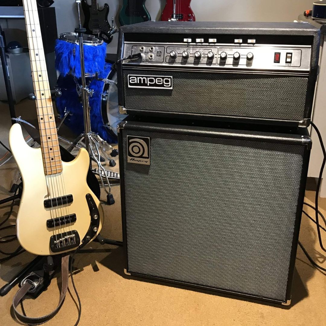 Angled front view of Ampeg SVT-212AV 2x12" 600W Bass Cabinet with Ampeg amp head on top of it and bass beside it in studio