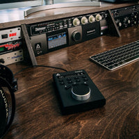 Music production equipment on a wooden desk with a keyboard and headphones.