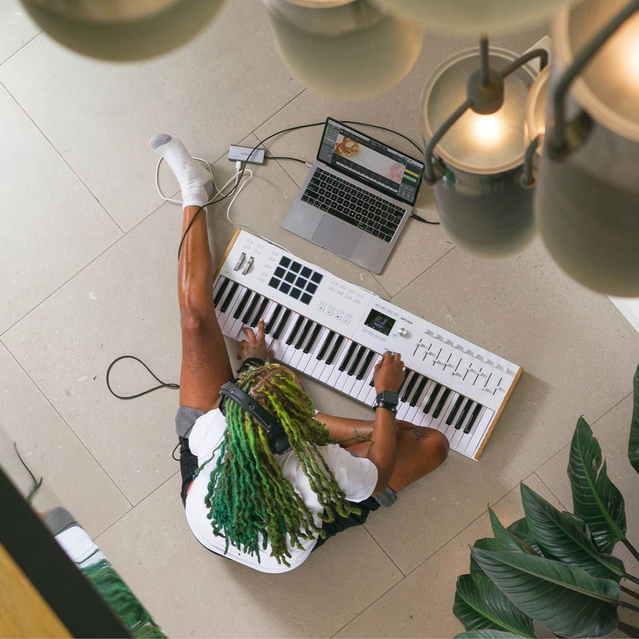 Musician playing with the Arturia KeyLab Essential 61 mk3 MIDI Controller while on the floor at home