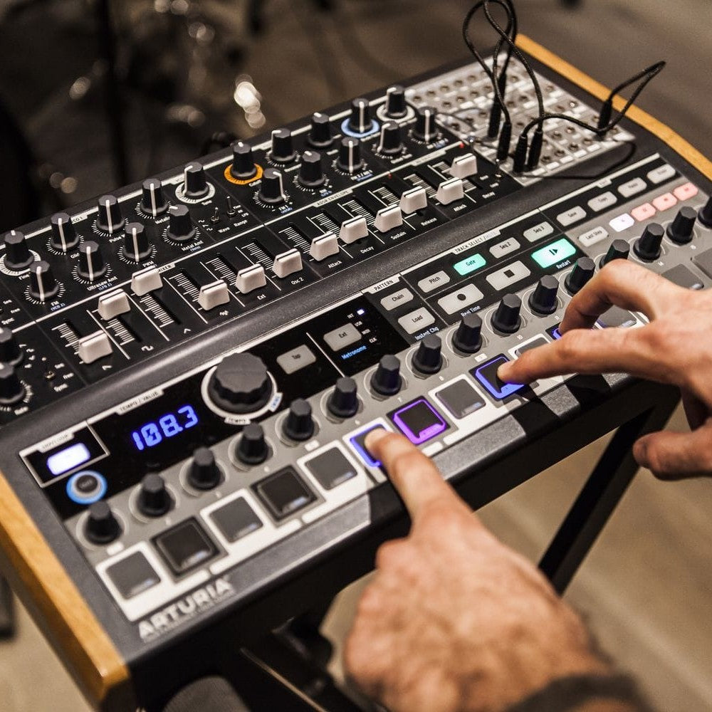 Angled view of Arturia MiniBrute 2S Noir Analog Synthesizer with musician sequencing on it in studio
