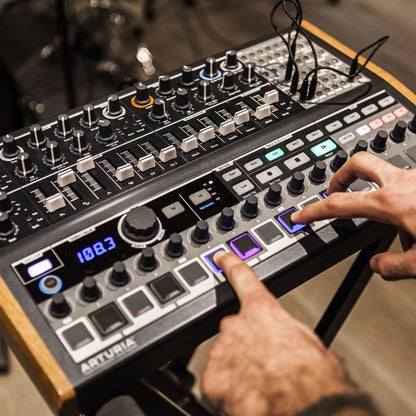 Angled view of Arturia MiniBrute 2S Noir Analog Synthesizer with musician sequencing on it in studio