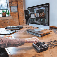 Studio engineer recording in studio utilizing the Audient ASP880 on wooden desk