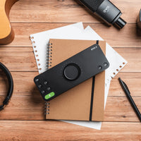 Top view of Audient EVO 8 on top of notebooks with other equipment scattered on top of wooden surface