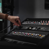 Audient ORIA in equipment rack with hand plugging in cable to input with other rackmount effects in studio