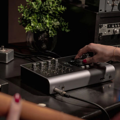 Angled front view of Audient iD44 MKII being used on dark desk with studio background