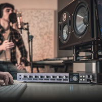 Angled front view of Audient iD48 on studio desk while recording vocalist in the background