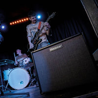 Angled front view of Blackstar ID:X 100 Combo Amplifier on stage venue with band performing in the background