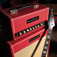 Angled close up view of Blackstar St. James TL50 Toby Lee Signature Amp Head and Cabinet with guitar leaning on it with living room background