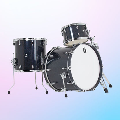 Angled view of British Drum Co. Lounge Series 22" US Club Kit Ravenglass on pink and blue gradient background