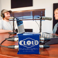 Blue Cloud Microphones Clouddlifter on a desk with a podcast setup in the background