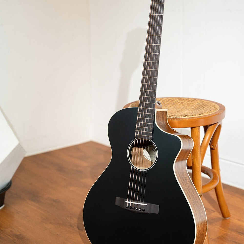 Close up view of Cort Core-MC Ovangkol Acoustic Electric Guitar (Black Top Semi Gloss) leaning on stool in room