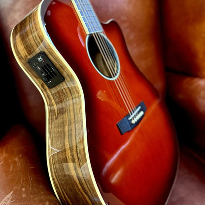 Close up angled view of Cort Exotic-GA Walnut Acoustic Electric Guitar on brown couch