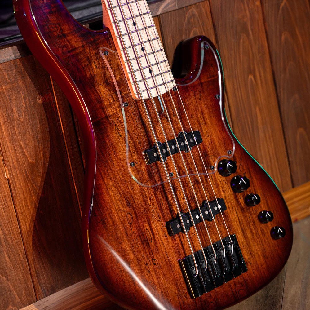 Angled close up view of Cort GB Fusion 5 String Electric Bass Guitar leaning on wooden surface in studio
