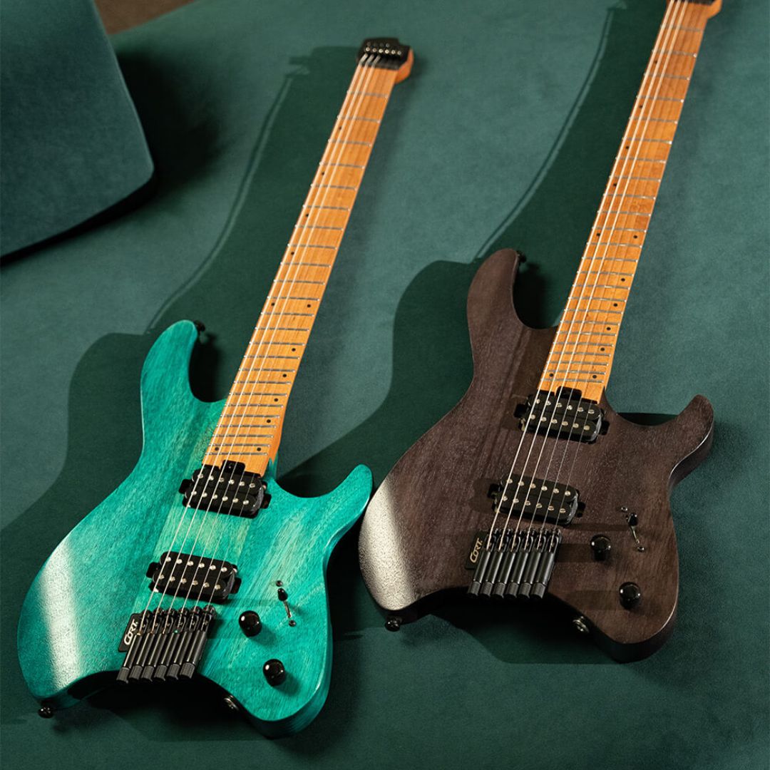 Front view of side by side Cort Space G6MS Electric Guitar Semi Gloss Turquoise and Semi Gloss Trans Black on green couch
