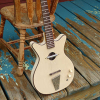 Close up angled view of Danelectro Convertible Acoustic Electric Guitar Cream leaning on wooden chair on wooden platform