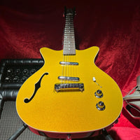 Angled close up view of Danelectro Fifty Niner Semi Hollow Electric Guitar Gold Top with amp and red cloth background