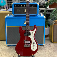 Close up front view of Danelectro '64XT Electric Guitar Red with guitar amplifier background in studio