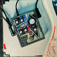 Top view of Death By Audio Crossover Fuzz with cables attached on concrete surface with guitar on the side