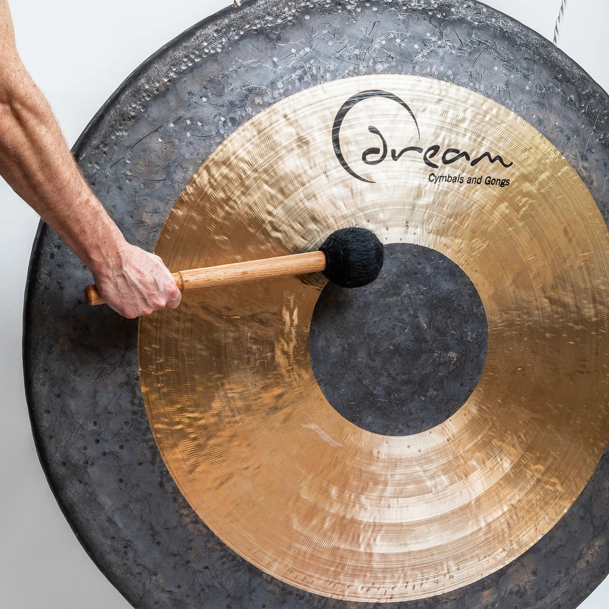 Close up angled view of arm hitting the Dream Cymbals CHAU52 Black Dot Chau 52" Gong with mallet
