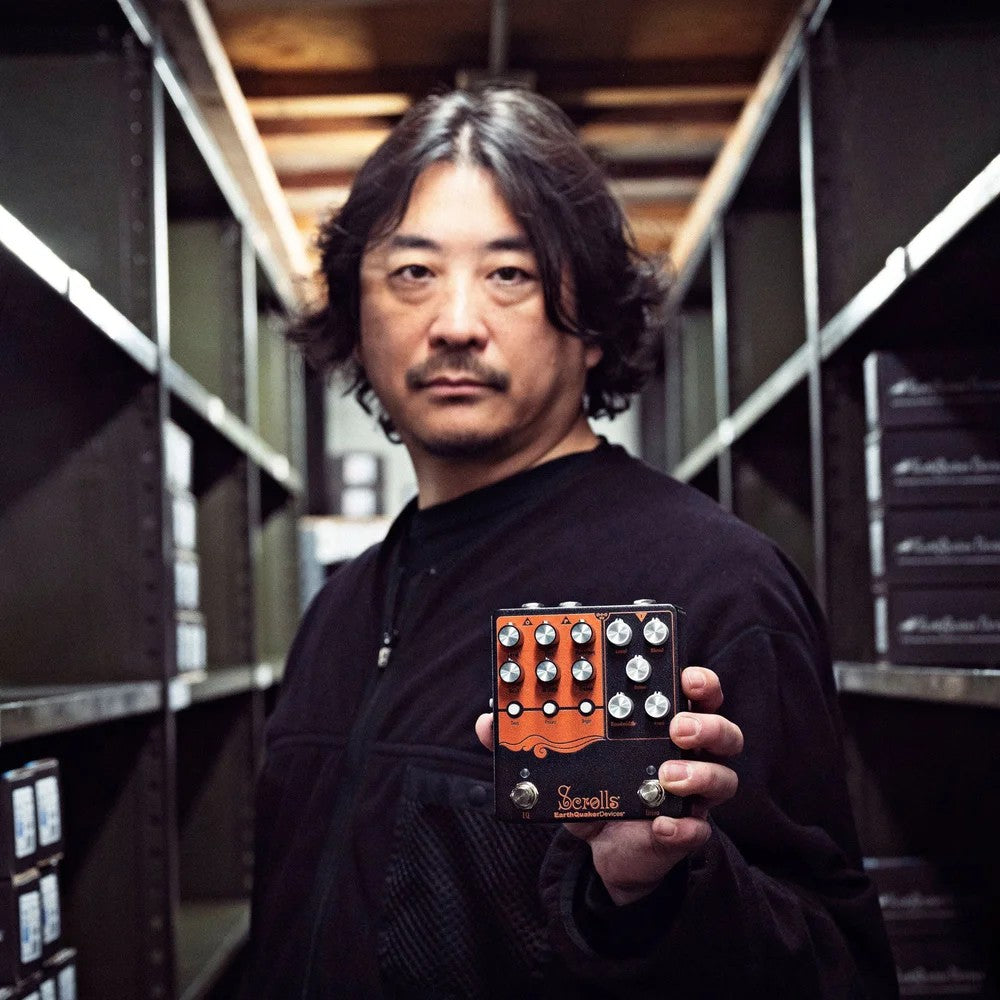 Kentaro holding the EarthQuaker Devices Scrolls Bass Odyssey Pedal in warehouse