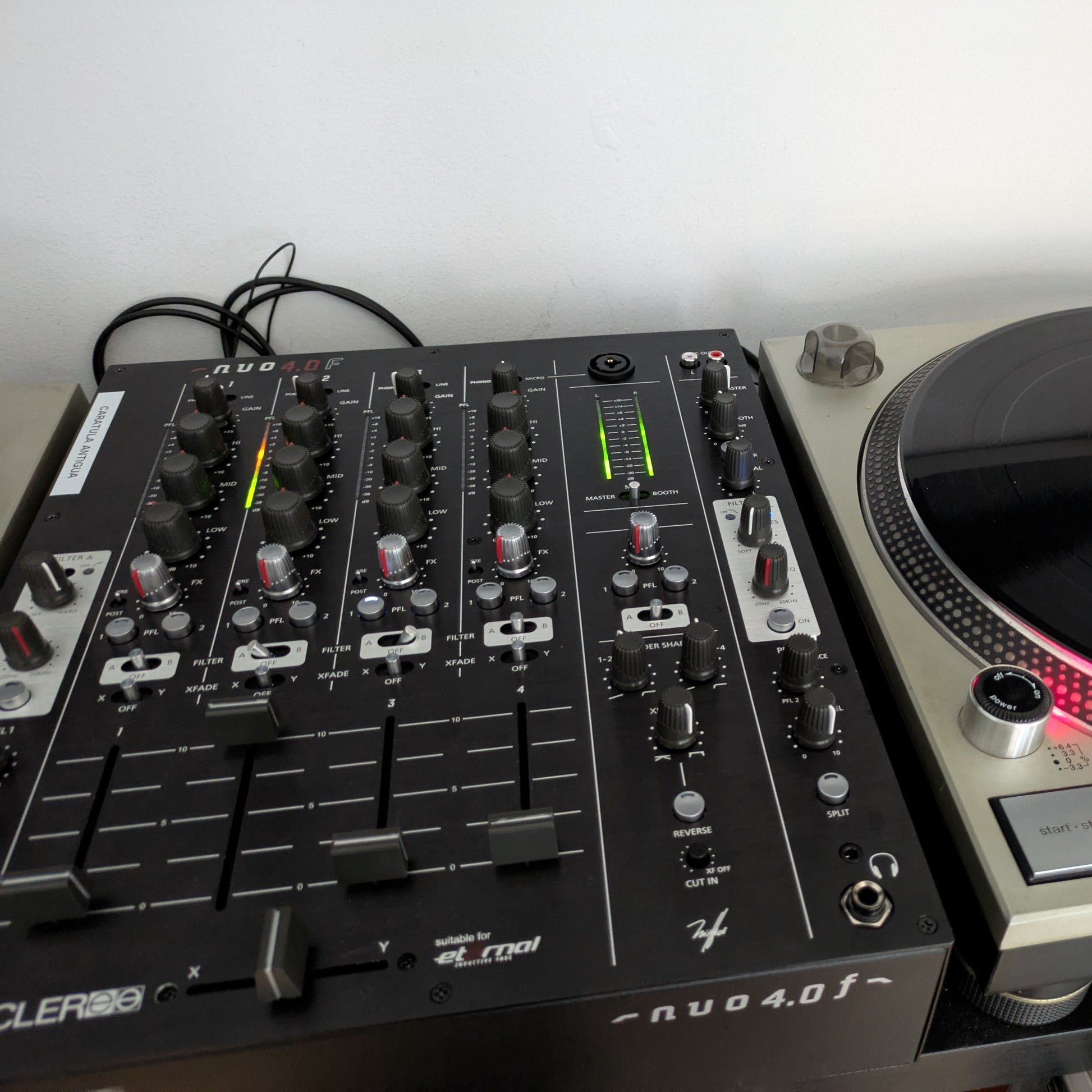 Angled front view of Ecler NUO4.0F Professional 4-Channel DJ Mixer Black attached to turntable
