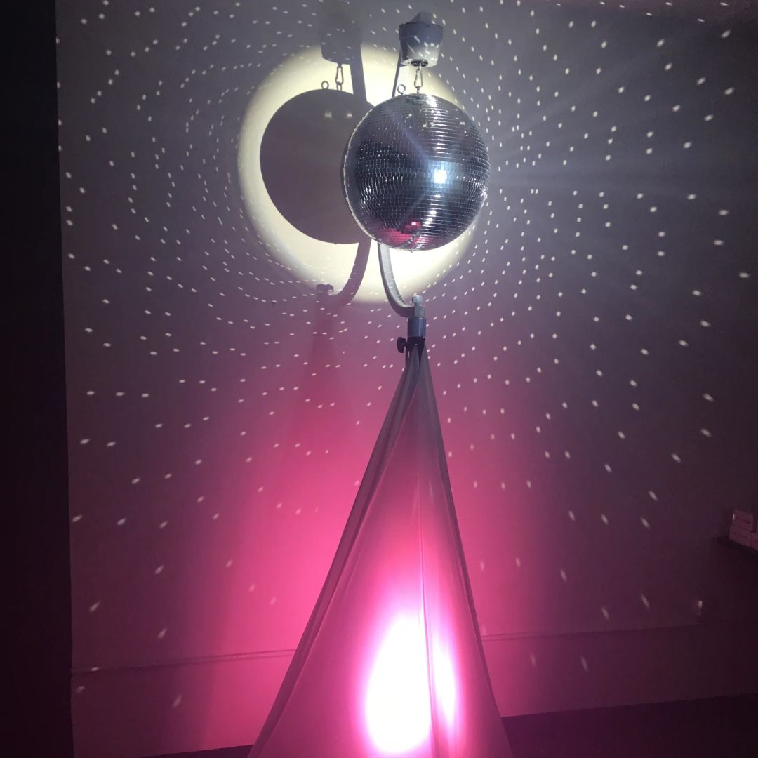 Front view of Eliminator Lighting Decor MBSK Mirror Ball Stand with Motor with pink lighting in dim room