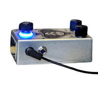 Side view of Flattley Bass Ace Tone Boost Pedal with power cable attached on white background