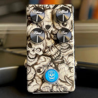 Top view of Flattley Bass Poison Ivy Bass Fuzz Pedal on black surface with guitars in the background