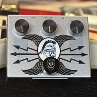 Top view of Flattley Silver Centurion Transparent Overdrive Pedal on black surface with guitar background