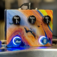 Top view of Flattley Solaris Pro Fuzz with Boost Pedal on top of guitar with studio background