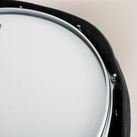 Close-up of a drum head with black rim on a beige background